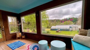 A room with large windows, a blue and pink rug, two white round tables, and a blue sofa.