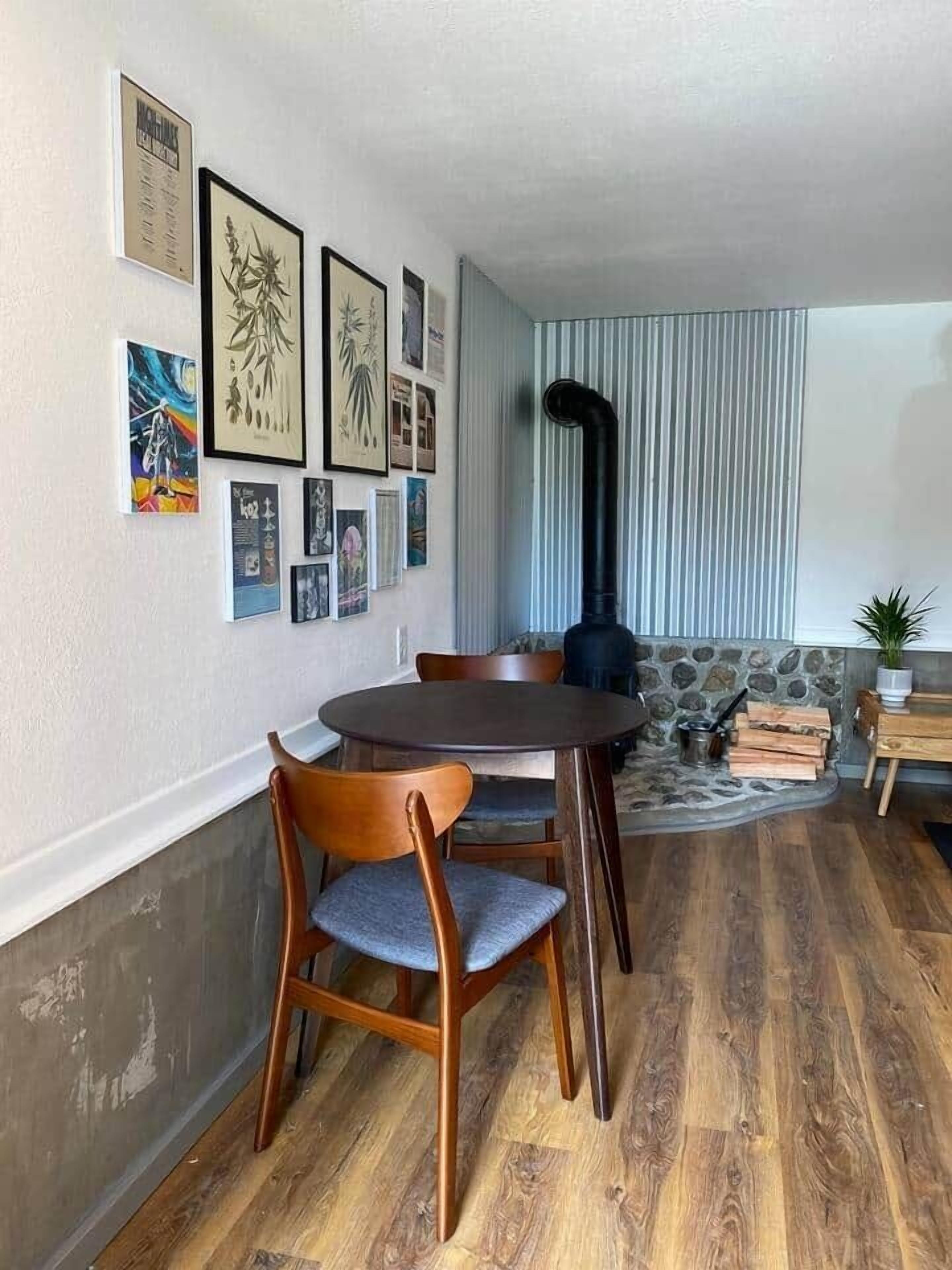 A dining area with a round table and chairs, a stone accent wall, and various framed artworks on the wall.