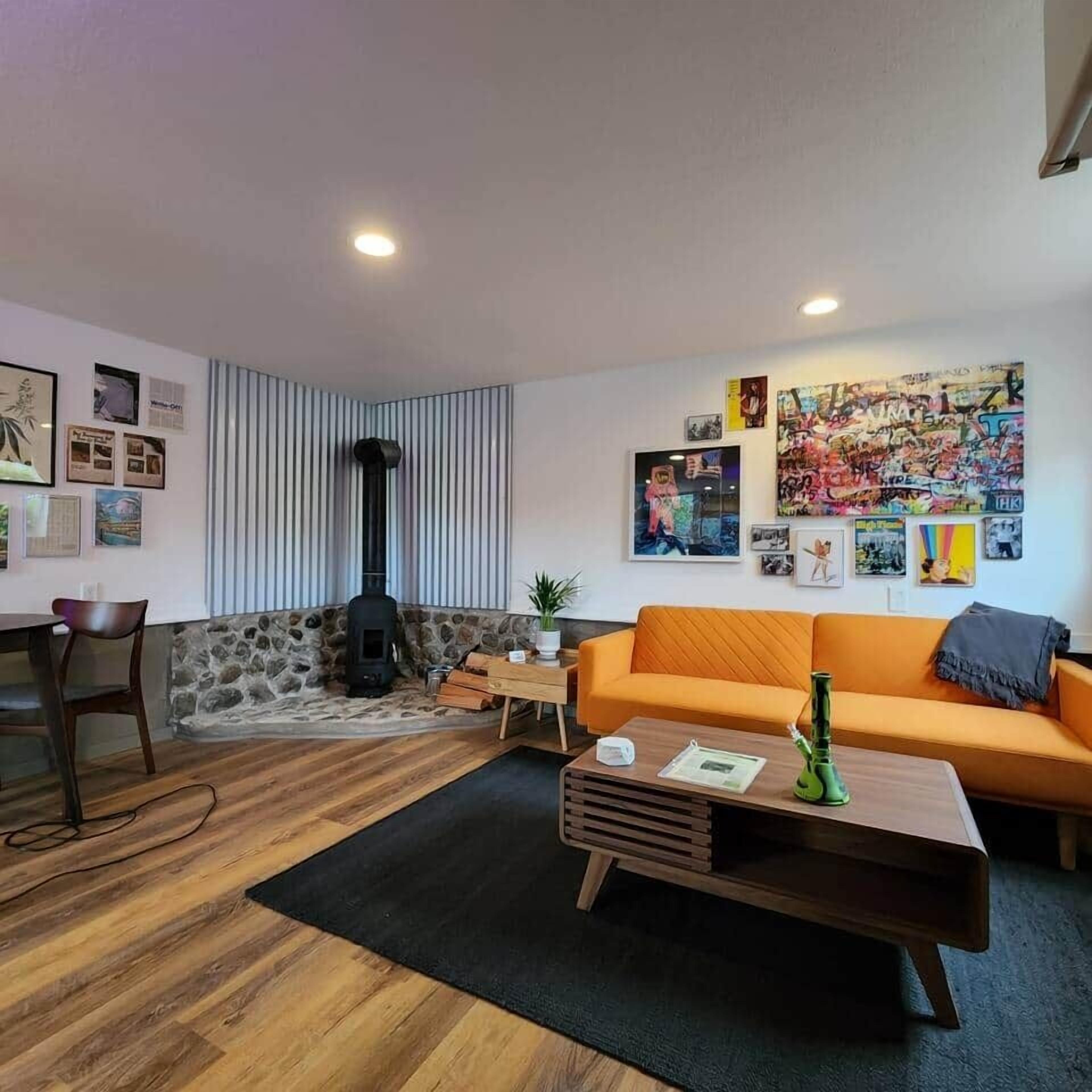 A cozy living room with a stone wall, a fireplace, a sofa, and various wall art.