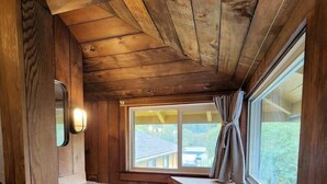 Ein Badezimmer einer Holzhütte mit Waschbecken, Spiegel und Fenster.