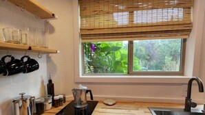 Eine moderne Küche mit einer schwarzen Induktionskochplatte, einem Edelstahl-Spülbecken und Holzregalen darüber.