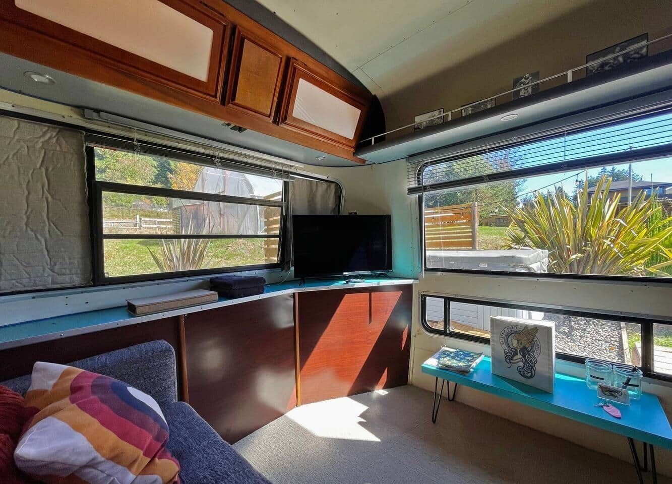En kompakt autocamper indretning med et tekøkken, et fladskærms-tv og et lille bord med pynt.