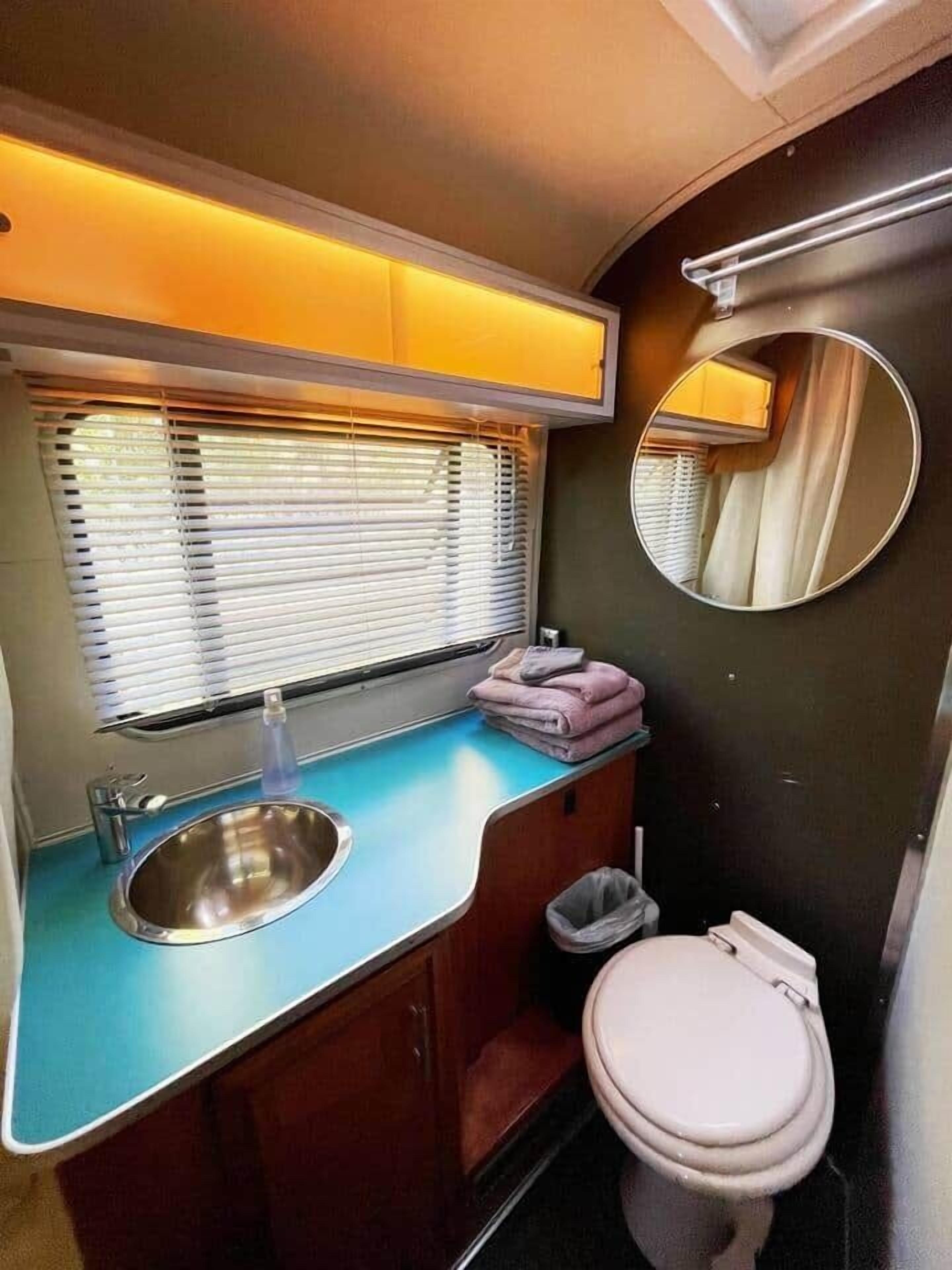 Un baño pequeño con lavamanos, inodoro y ventana con persianas.