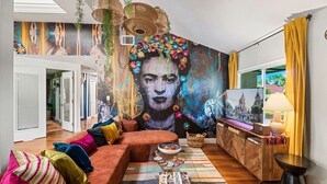 A living room with a large mural, a sofa, a coffee table, and a TV stand.