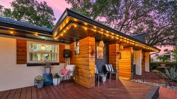 A wooden house with a deck, outdoor seating, and string lights.