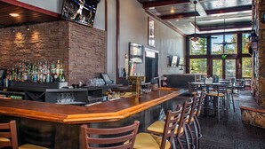 A bar area with a wooden counter, multiple stools, and a brick wall backdrop. - Relaxed Luxury 2BR at Grand Timber Lodge – Mountain-View Retreat in Breckenridge (Breckenridge)