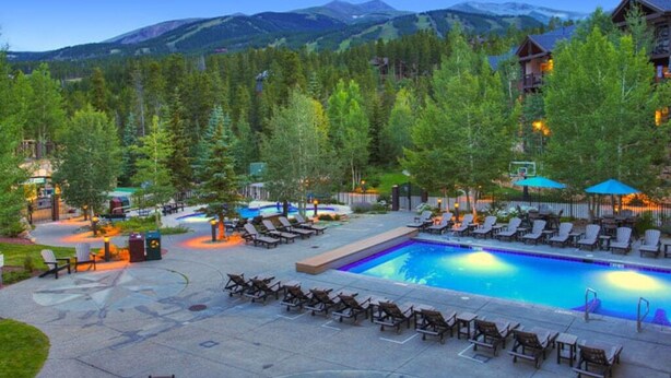 A pool area with lounge chairs and a view of mountains. - Relaxed Luxury 2BR at Grand Timber Lodge – Mountain-View Retreat in Breckenridge (Breckenridge)