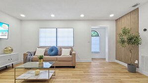 Un salon moderne avec un canapé, une table basse en verre et une plante en pot.