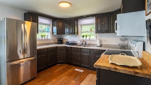 Una cocina moderna con gabinetes oscuros, electrodomésticos de acero inoxidable y una encimera de madera.