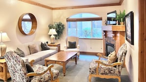 A cozy living room with a sofa, two armchairs, a coffee table, a TV, and a fireplace. - 1049 | King Villa | Full Kitchen | Pool & Hot Tub (Midway)