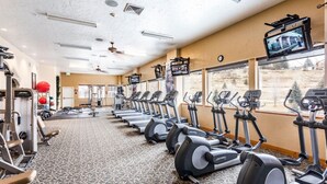 Une salle de sport équipée de tapis de course, de vélos elliptiques et d’appareils de musculation.