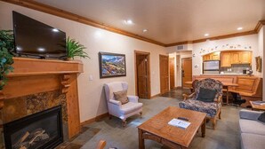 A living room with a fireplace, a television, and a kitchen area. - 1072 | King Villa w/ Kitchen | Near Park City (Midway)
