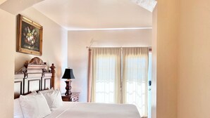 A neatly made bed with white linens, a wooden headboard, a bedside lamp, and a framed floral painting on the wall. - 1057 | King Villa w/ Kitchen Near Soldier Hollow (Midway)