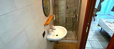 A bathroom with a shower, two sinks, a mirror, and a wooden ceiling.