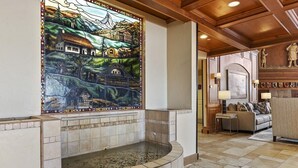 Un área de spa con una pared de mosaicos, una bañera de piedra y un rincón de descanso con sofá y lámparas.
