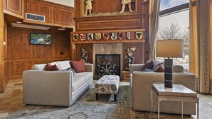 Un salón amplio con chimenea, paneles de madera y una colección de escudos en la pared.