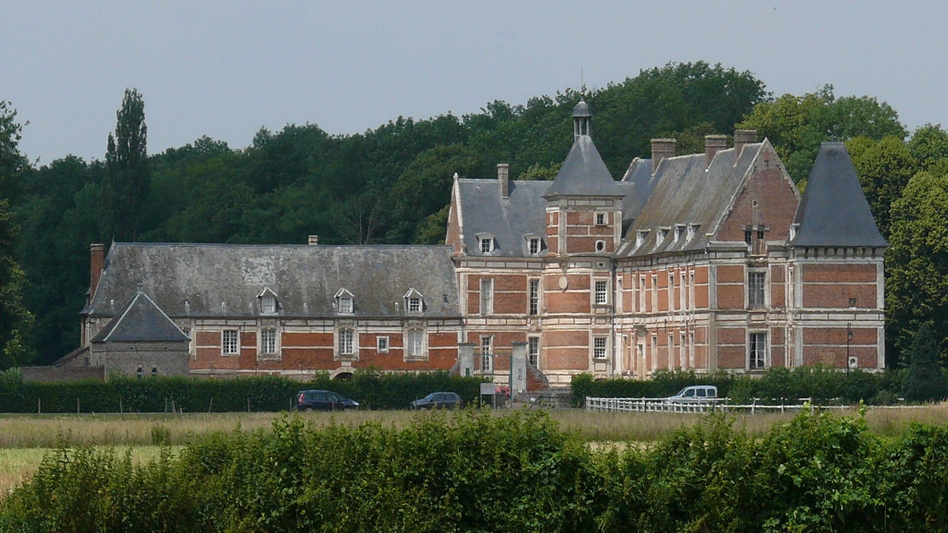 Un grand bâtiment historique doté de plusieurs ailes et d’une tour centrale imposante.