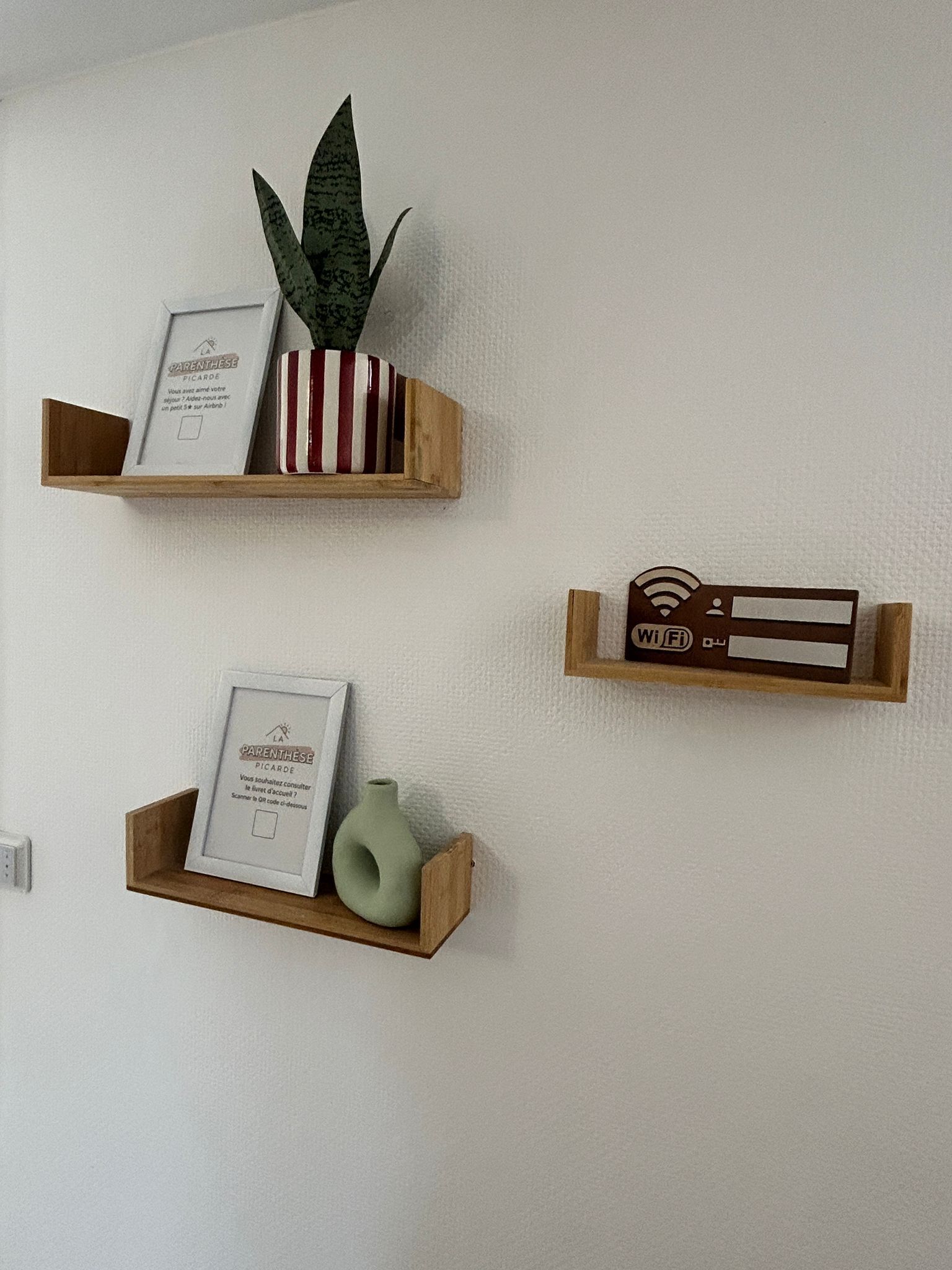 Trois étagères murales en bois, sur lesquelles sont disposés divers objets.
