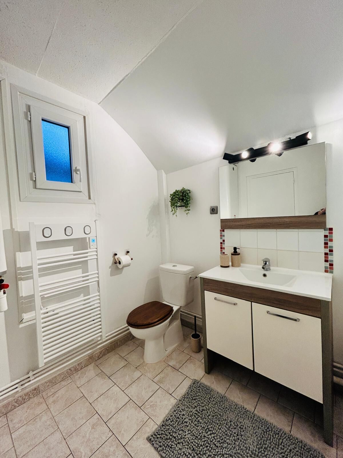 Ein kleines Badezimmer mit Toilette, Waschbecken und einem Spiegel.