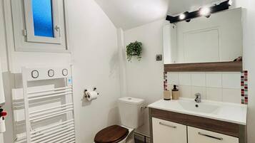 Ein kleines Badezimmer mit Toilette, Waschbecken und einem Spiegel.