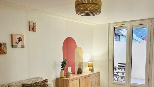 Sala de estar con sofá, mesa de comedor y un mueble aparador. Se observan obras de arte en las paredes y un lámpara colgante.