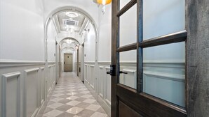 A hallway with checkered flooring, white walls, and a wooden door with frosted glass panels.