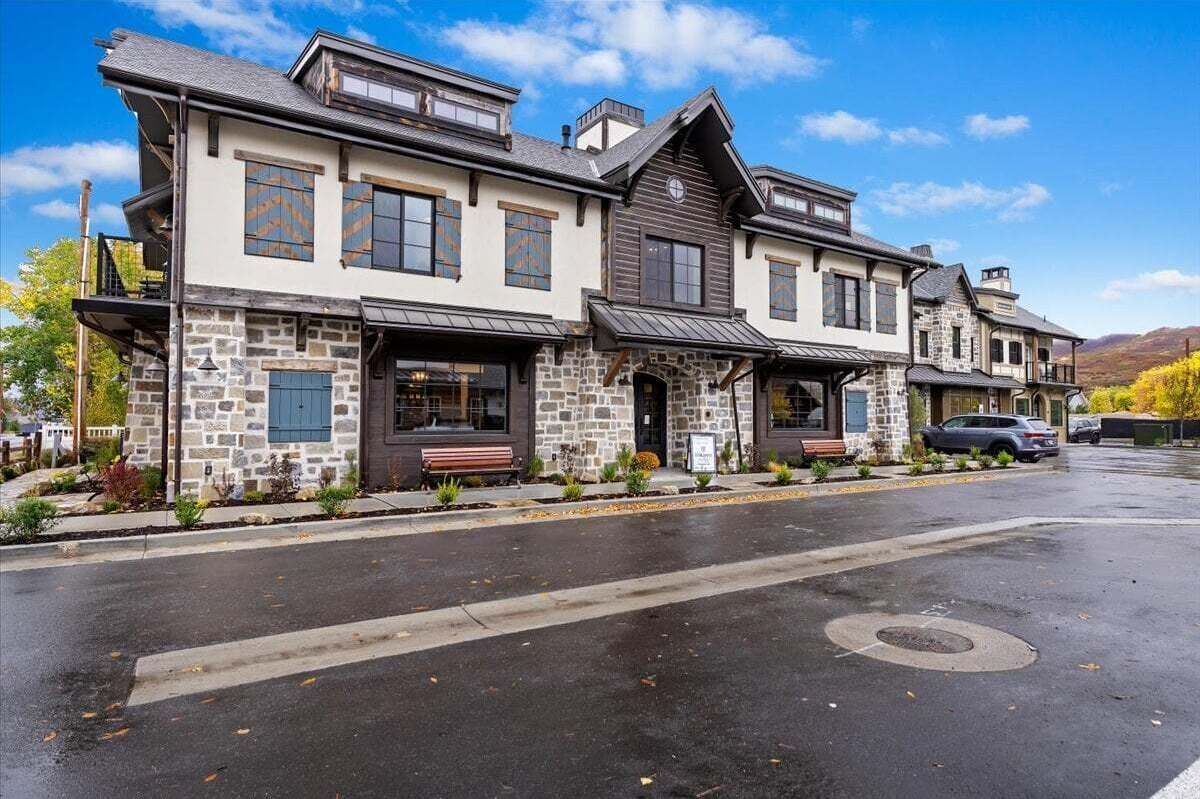 A two-story building with a stone facade, multiple windows, and a covered front porch.
