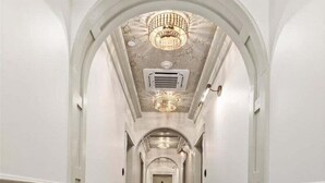 A hallway with a checkered floor, white walls, and a chandelier.