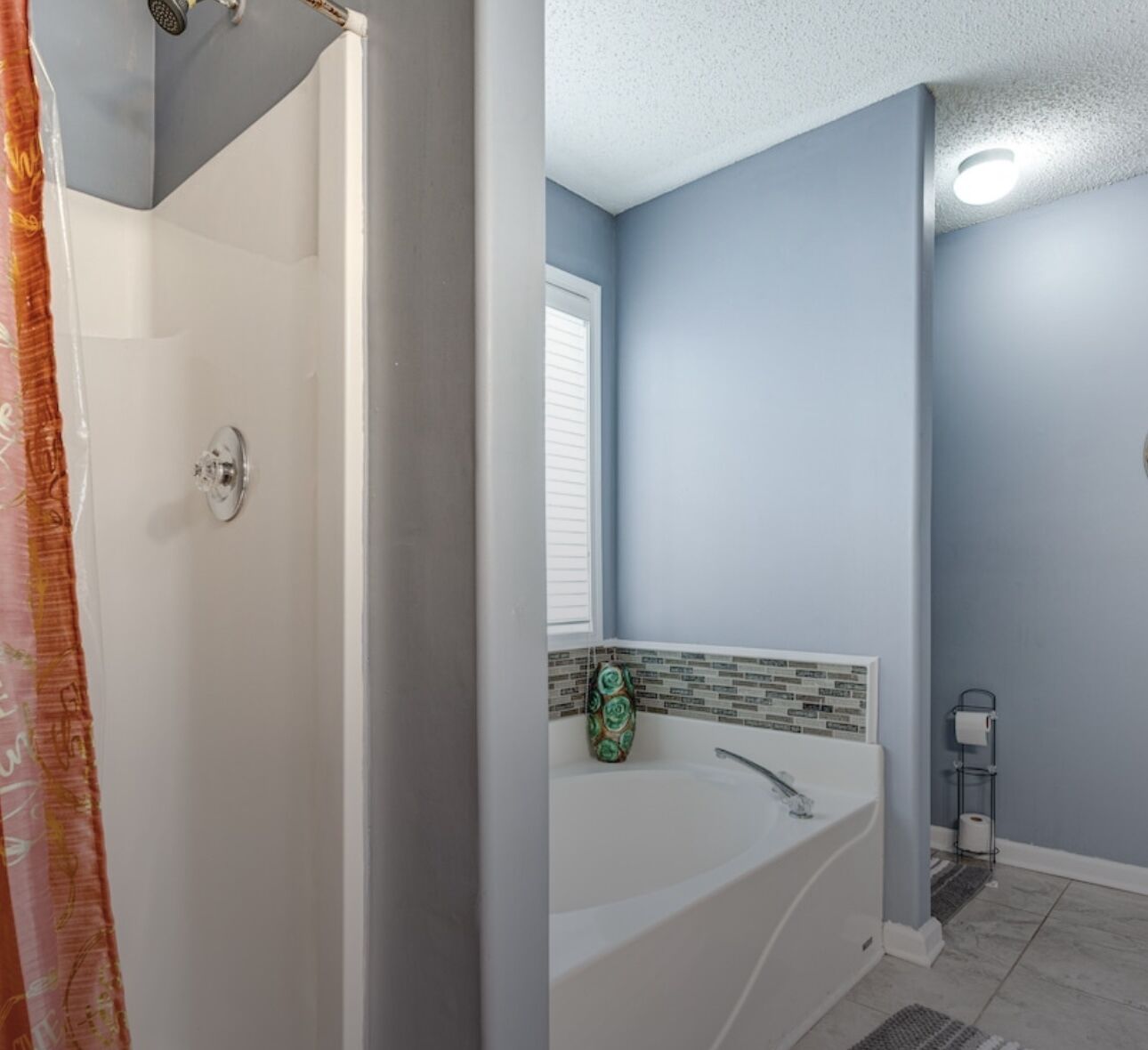 Une salle de bain avec une douche, une baignoire et une fenêtre.