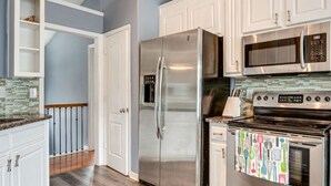 A kitchen with white cabinets, stainless steel appliances, a microwave, and a stove. - Cozy Monroe Villa Getaway-Poolside Fun & Pet-Friendly! (Monroe)