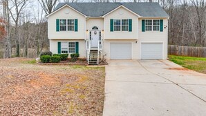 A two-story house with a front garage, a small front yard, and a wooden fence in the background. - Cozy Monroe Villa Getaway-Poolside Fun & Pet-Friendly! (Monroe)