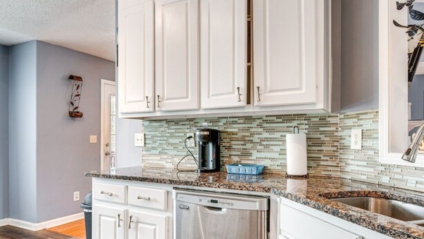 A modern kitchen with white cabinets, a stainless steel dishwasher, and a tiled backsplash. - Cozy Monroe Villa Getaway-Poolside Fun & Pet-Friendly! (Monroe)