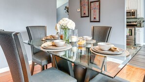 A modern dining area with a glass table, grey upholstered chairs, and a chandelier. - Cozy Monroe Villa Getaway-Poolside Fun & Pet-Friendly! (Monroe)
