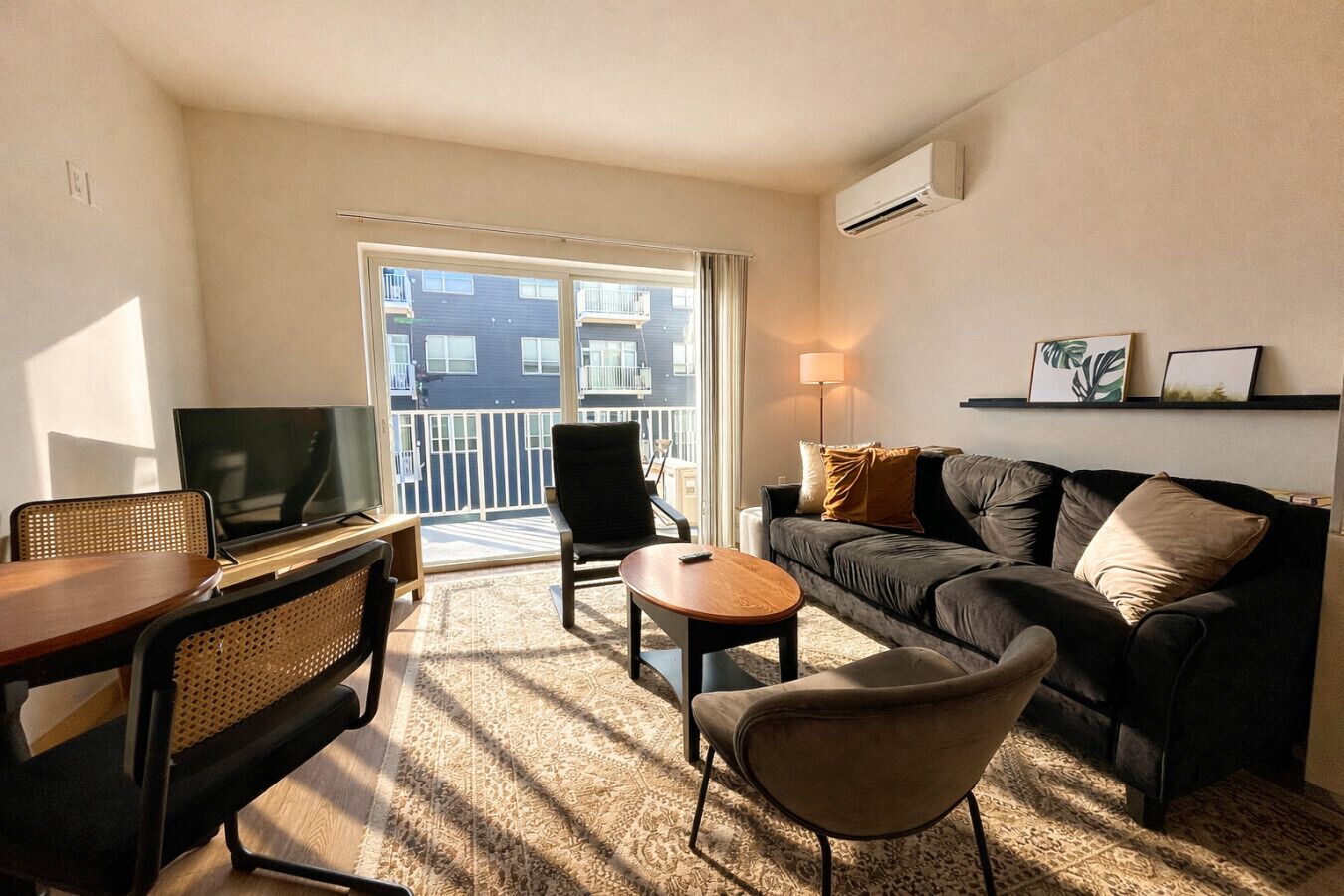 Ein modernes Wohnzimmer mit Sofa, Sessel, Couchtisch und Fernseher.
