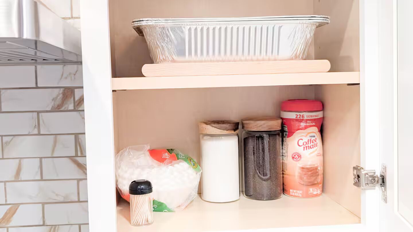 Una despensa de cocina con un recipiente de vidrio para hornear, un bote de café, un frasco y un saco de harina.