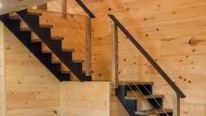 A wooden interior with a staircase and a wood-burning stove.