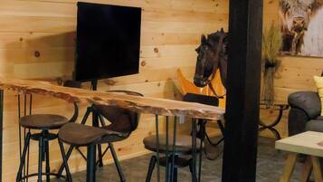 A wooden interior with a bar area, stools, a television, and a horse sculpture.