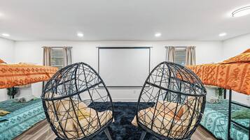 Une chambre avec deux lits, un fauteuil noir de forme circulaire et une grande fenêtre.