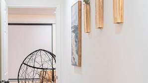 A hallway with a modern chair, a framed artwork, and three wooden vases on the wall. - Spacious 5BR Athens Home | Massage Chairs & Fire Pit | Sleeps 12 | Near UGA (Athens)