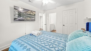 A bedroom with a bed, a ceiling fan, a door, and a wall-mounted TV. - Spacious 5BR Athens Home | Massage Chairs & Fire Pit | Sleeps 12 | Near UGA (Athens)