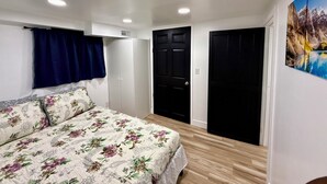 A bedroom with a floral bedspread, a wardrobe, a black door, and a painting of a mountain landscape. - Brilliant bungalow in Midvale ski/hike, fishing, recreational activities (Midvale)