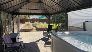 A covered patio area with a hot tub, outdoor seating, and garden beds. - Brilliant bungalow in Midvale ski/hike, fishing, recreational activities (Midvale)