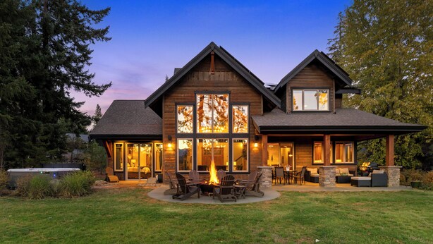 Una amplia casa de madera con una chimenea exterior y zona de estar al aire libre.