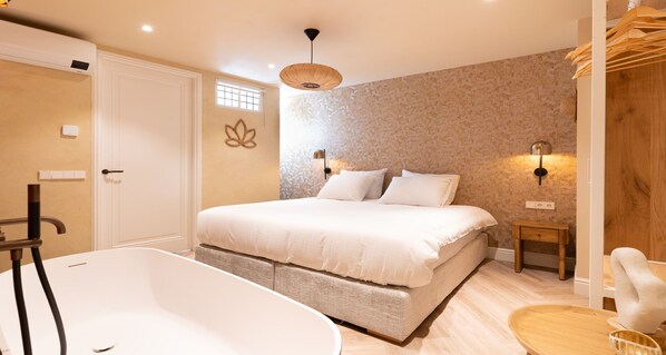 Ein Schlafzimmer mit einem großen Bett, einer Badewanne und einem kleinen Nachttisch.