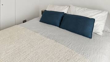 A bed with a textured bedspread and two pillows, one dark blue and one white striped.
