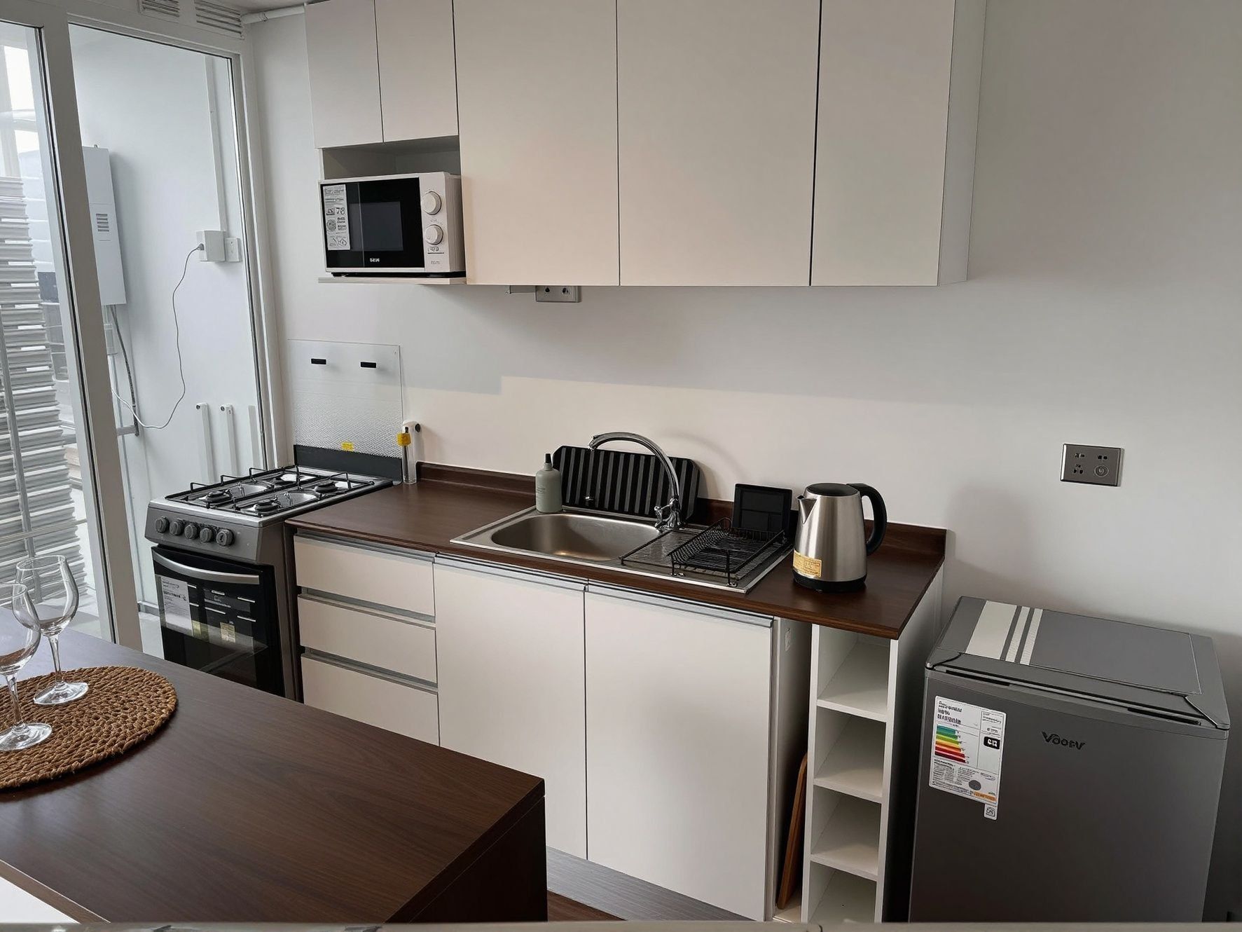 A compact kitchen with a microwave, stove, sink, and a small refrigerator.