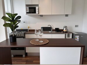 A modern kitchen with a microwave, stove, sink, and a small refrigerator.