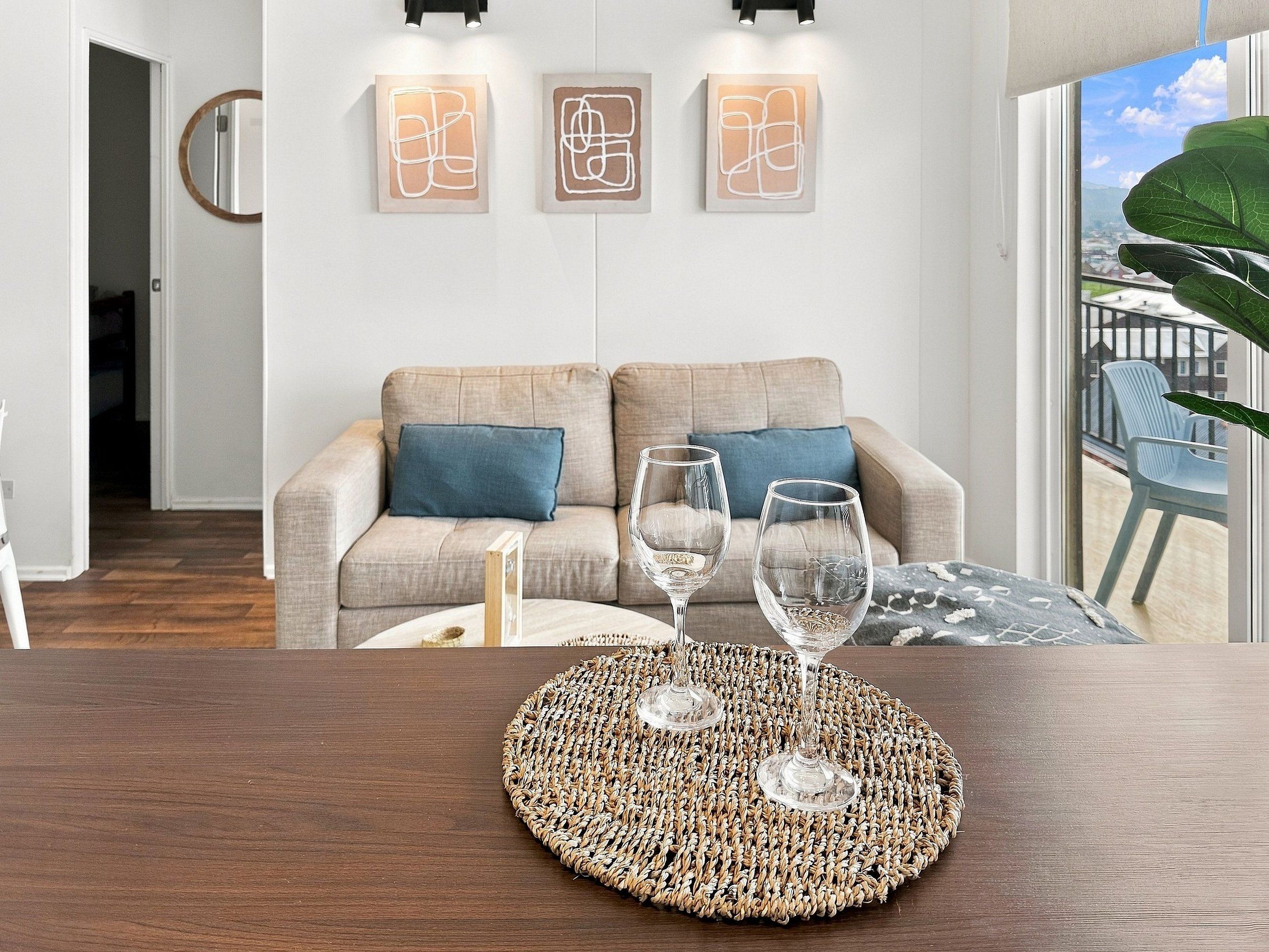 Sala de estar com sofá, duas taças de vinho e arte abstrata na parede.