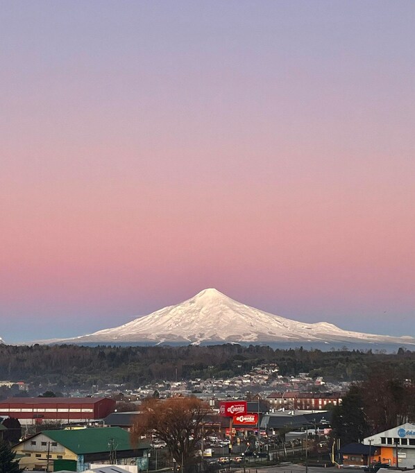 A snow-capped mountain with a town in the foreground. - Oceana Suites Alto Panorámico (Villarrica)