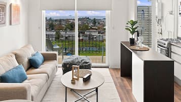Un apartamento moderno con balcón, cocina y sala de estar con sofá y mesa de centro.